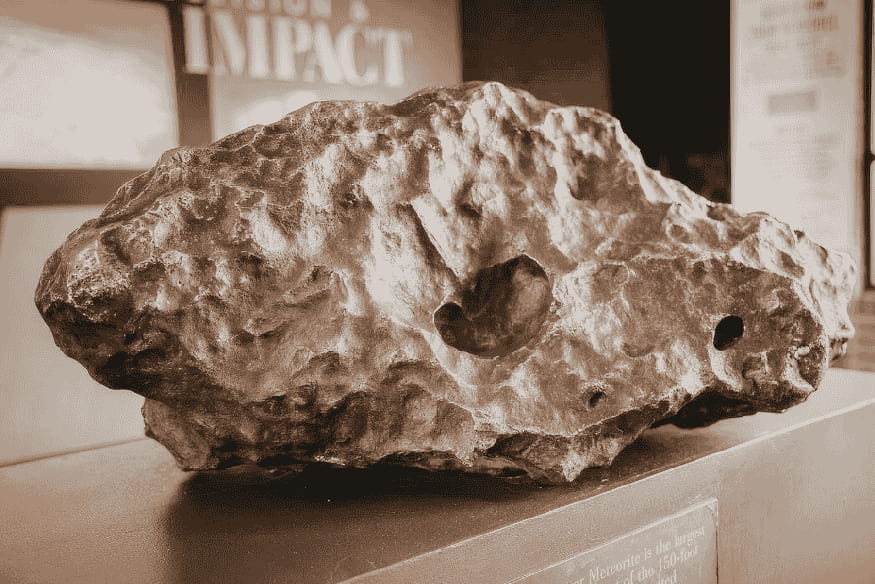 Meteorito exposto em museu, exemplo de fragmento rochoso ligado ao estudo dos meteoros e de sua origem no espaço.