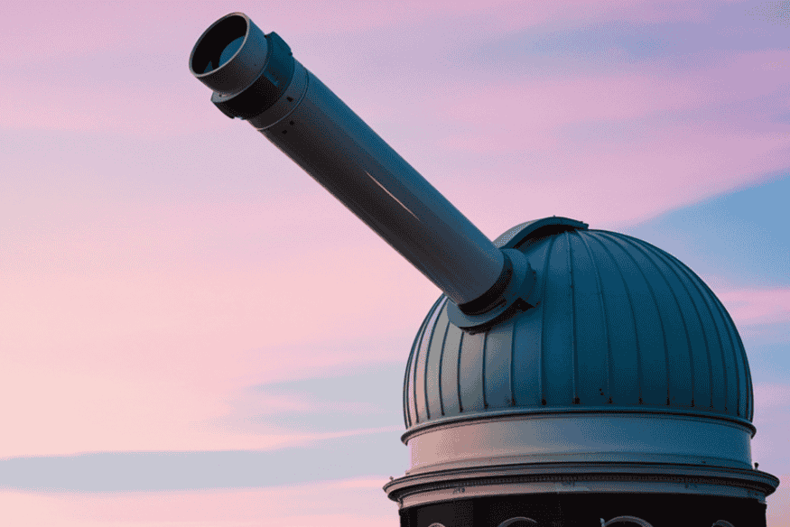 Cúpula de observatório astronômico com telescópio apontado para o céu, símbolo de pesquisa e estudo de eclipses.