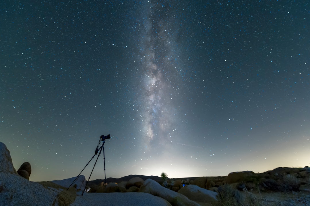 Astronomo amador observando ceu noturno com telescopio em local escuro no Brasil