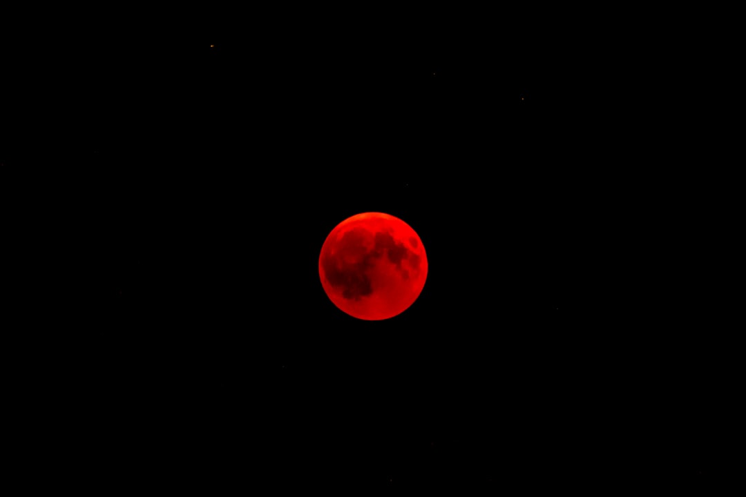Lua vermelha durante eclipse lunar total com céu estrelado ao fundo
