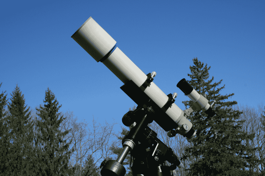 Telescópio em montagem apontado para o céu, usado em observações astronômicas para estudar o Sol e eclipses solares.
