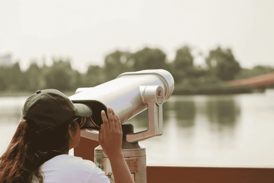 Pessoa observando com binóculo em ponto de observação, prática recomendada para iniciantes em eventos de astronomia.
