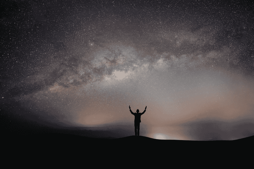 Pessoa observando o céu estrelado, cena que remete à Via Láctea visível da Terra em noites escuras.
