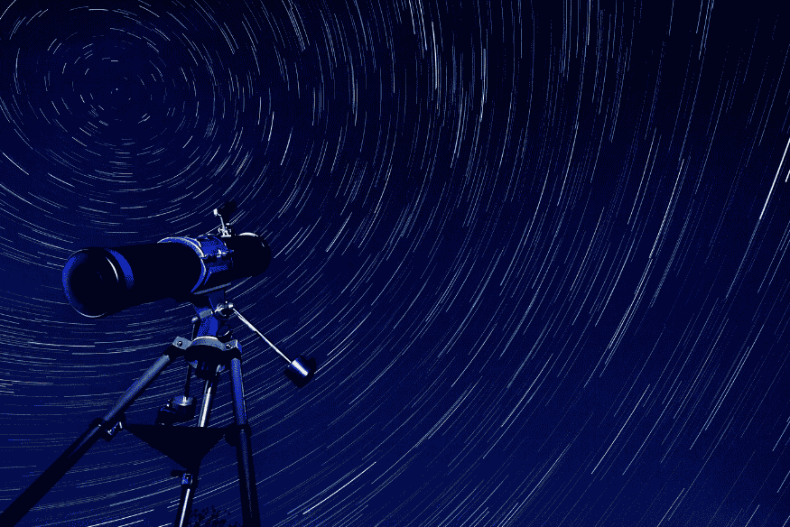 Telescópio apontado para o céu com trilhas de estrelas em longa exposição, representando como os astrônomos medem distâncias no espaço.