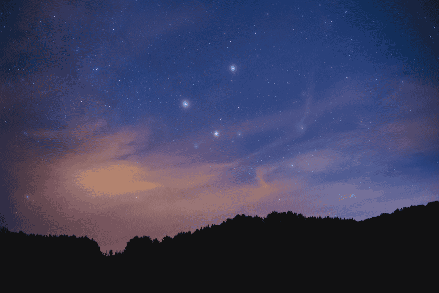 Céu noturno com estrelas alinhadas acima do horizonte, cenário ideal para fotografar conjunções planetárias com longa exposição.