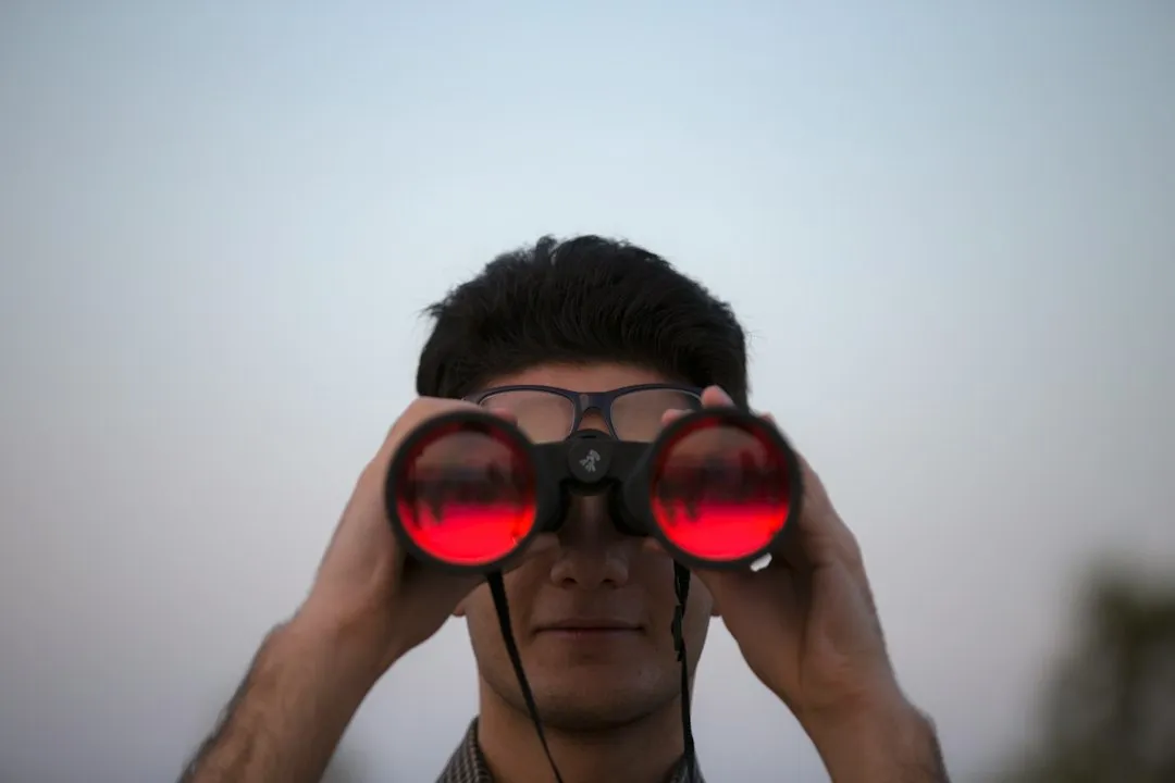 Pessoa usando binoculos para observar o ceu estrelado a noite